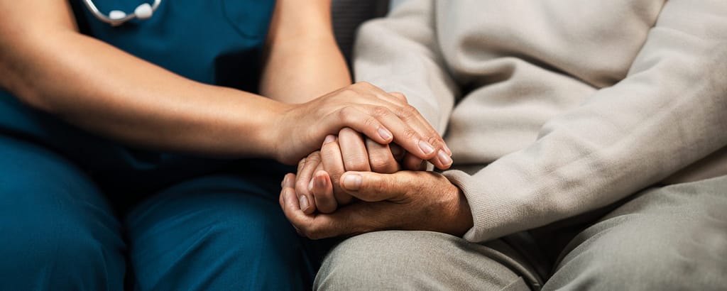 Shows whole-person care in action with Nurse praying with Elderly patient